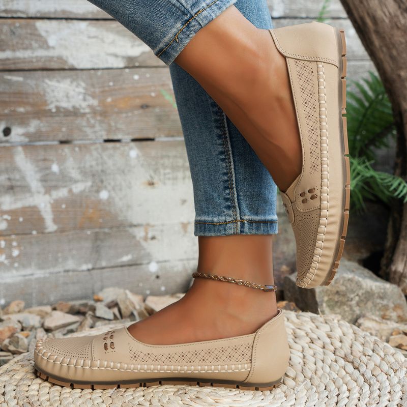 Beige women's wide fit leather loafers with stitched edges, side view on feet