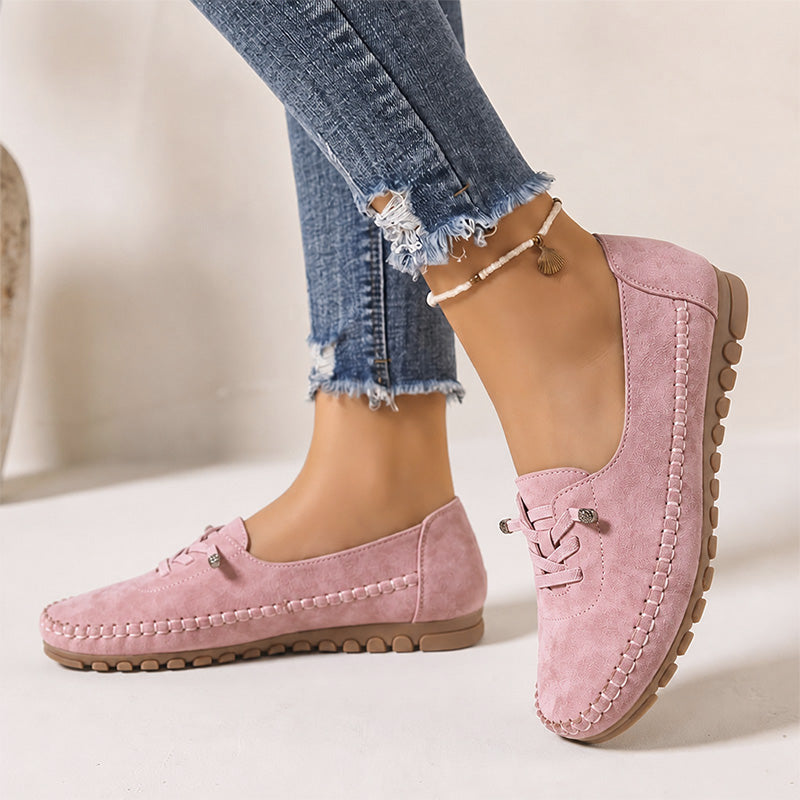 Pink women's wide fit suede loafers with brown soles, side view on feet