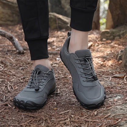 Grey unisex wide toe box lace-up hiking shoes worn on a woodland trail