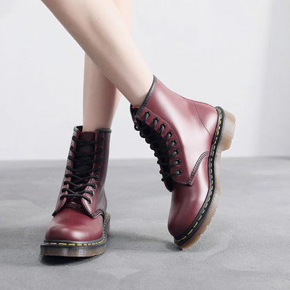 Burgundy lace-up combat ankle boots with chunky treaded soles, worn with trousers