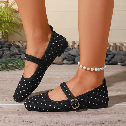 Black polka-dot women's Mary Jane flats with low heels, side view on feet