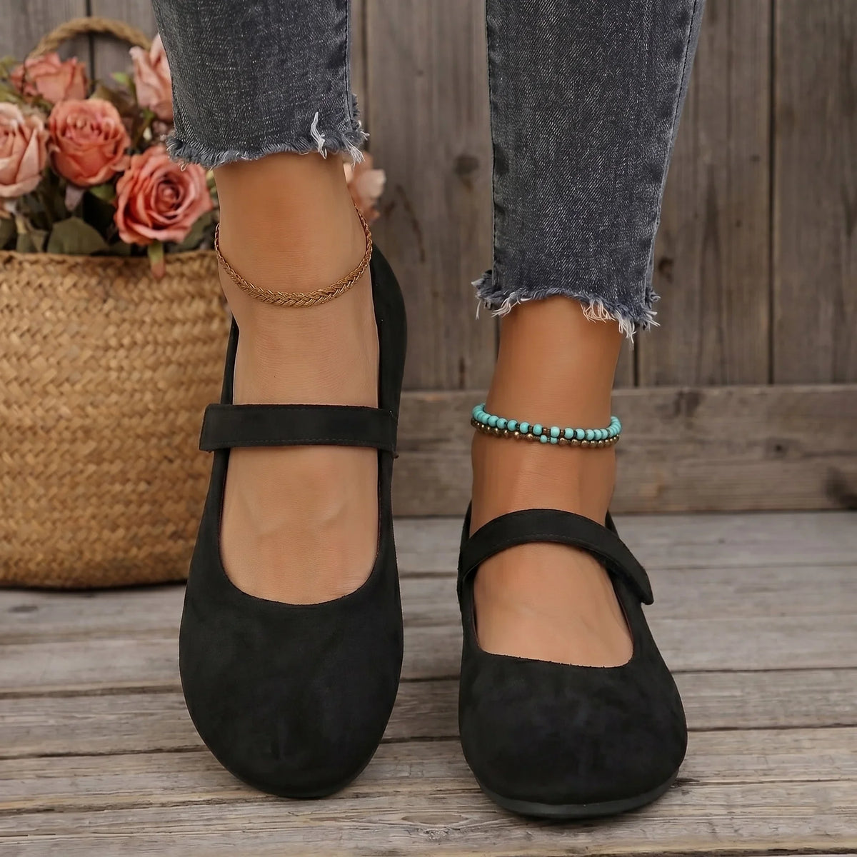 Women's black Mary Jane flats worn on a wooden deck, front view