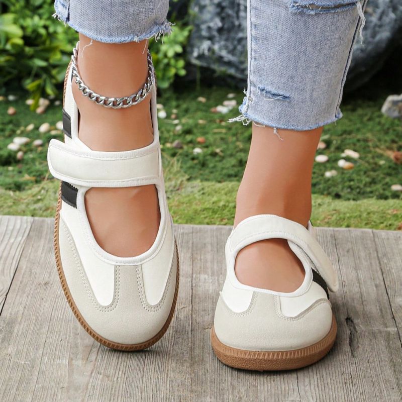 Cream women's Mary Jane trainers with contrasting black details, front view on feet
