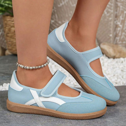 Blue and white women's Mary Jane trainers with adjustable straps, close-up on feet