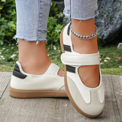 Cream women's Mary Jane trainers with black side stripes, close-up on feet