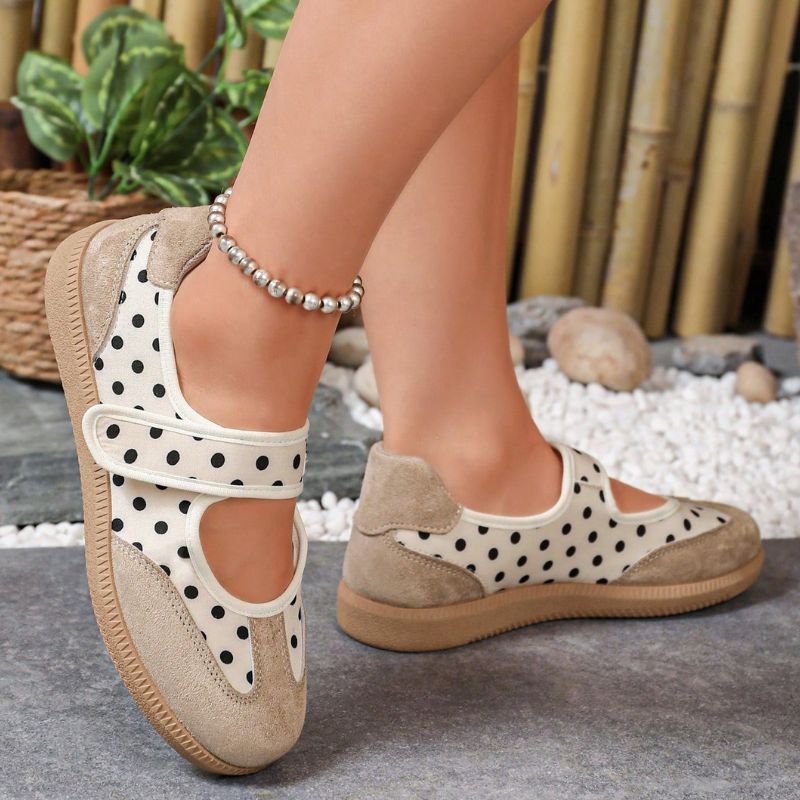 Beige polka-dot women's Mary Jane trainers showing the heel and strap on feet