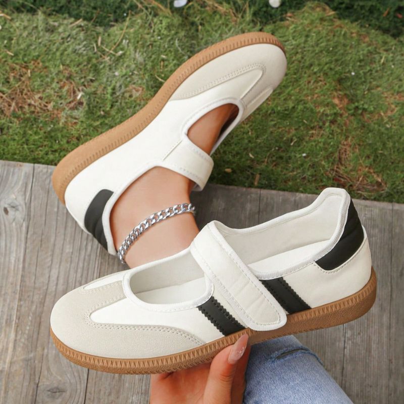 Cream and black women's Mary Jane trainers showing the strap and gum sole