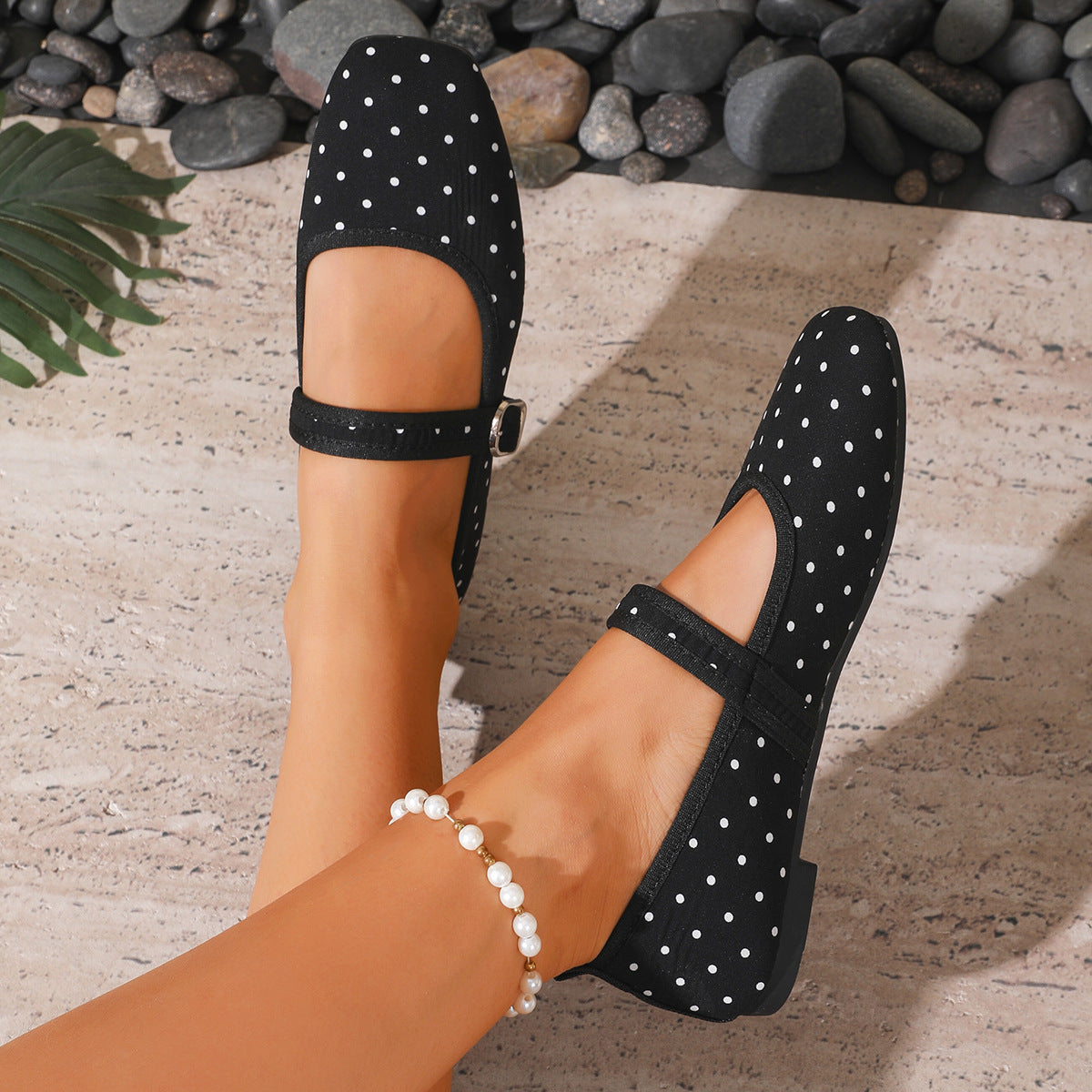 Black women's Mary Jane flats with white polka dots and buckle straps, top view on feet