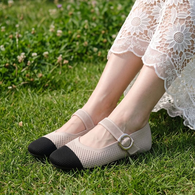 Beige and black Mary Jane flats with square toe and buckle strap worn on grass