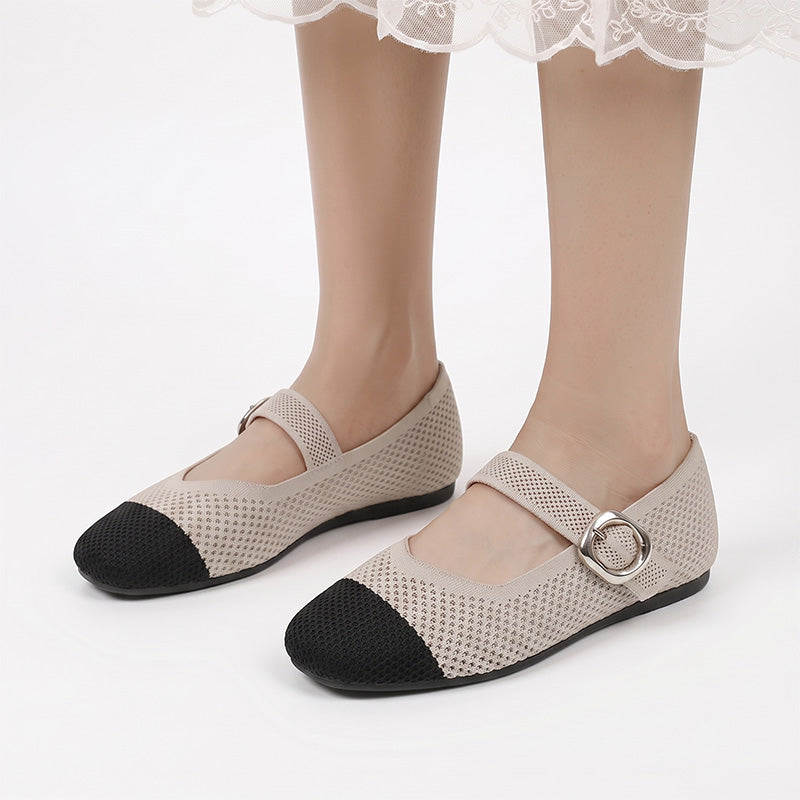 Beige and black Mary Jane flats with buckle straps worn from the front