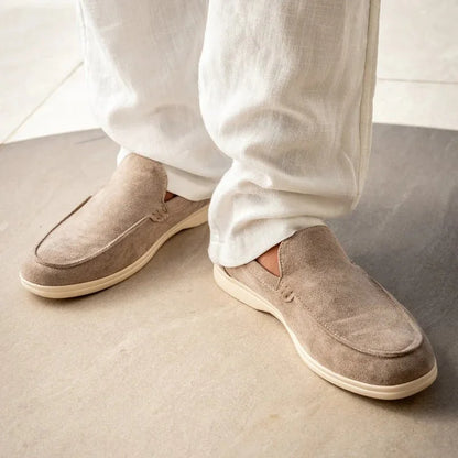 Beige men's slip on loafers worn with light trousers, side view