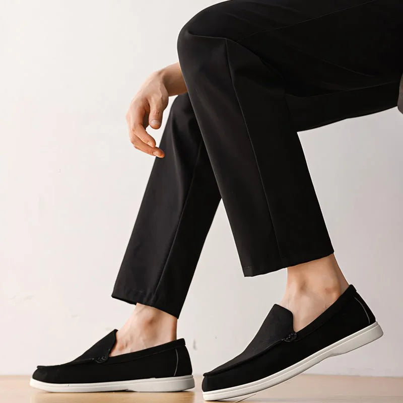 Black men's wide fit loafers worn with dark trousers, full side view