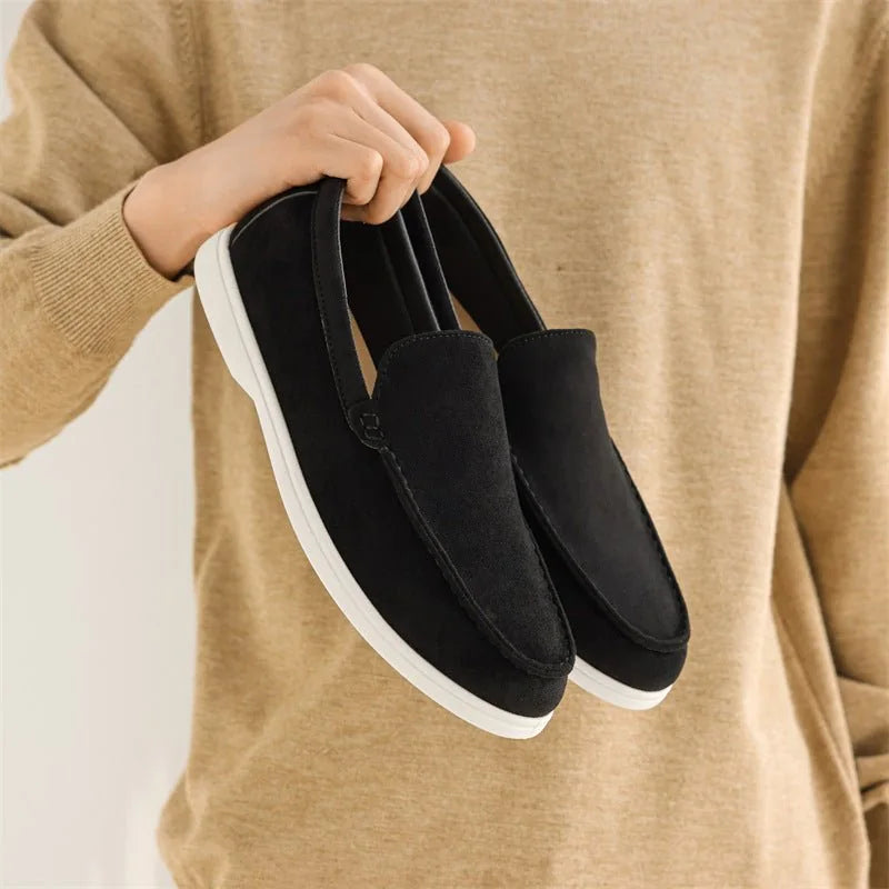 Black men's slip on loafers held in front of a tan jumper