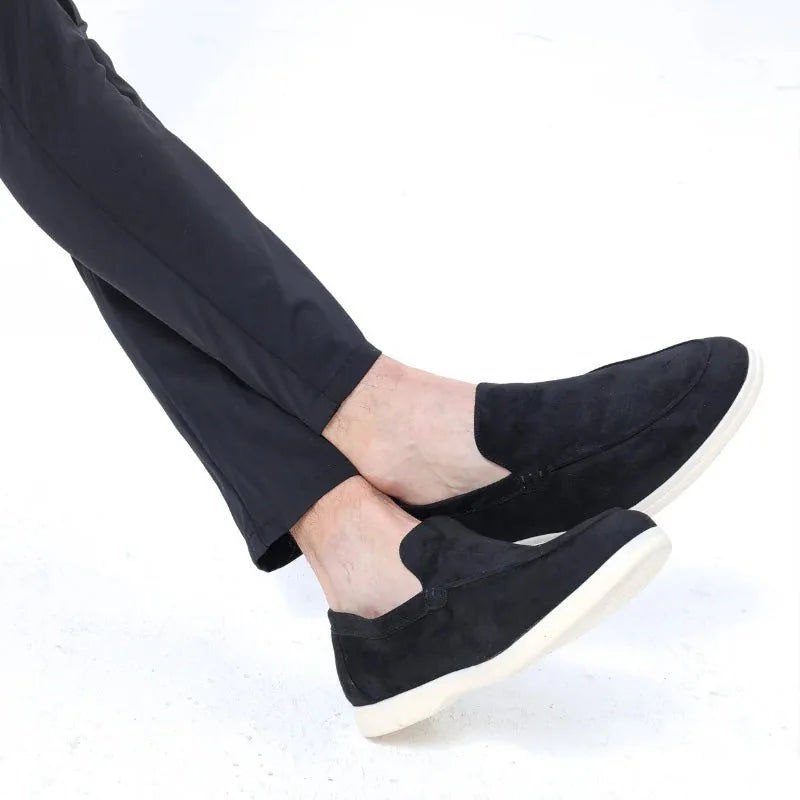 Black men's slip on loafers worn with dark trousers, close side view