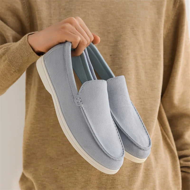 Fog blue men's loafers held in front of a tan jumper