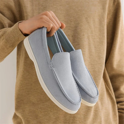 Fog blue men's loafers held in front of a tan jumper