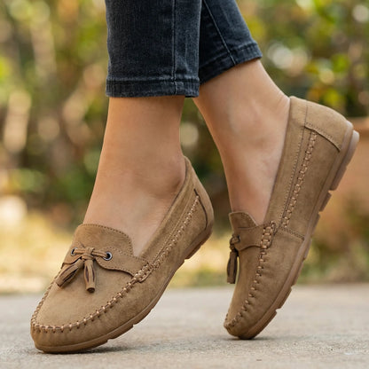 Brown slip on loafers for women, worn outdoors on a garden path