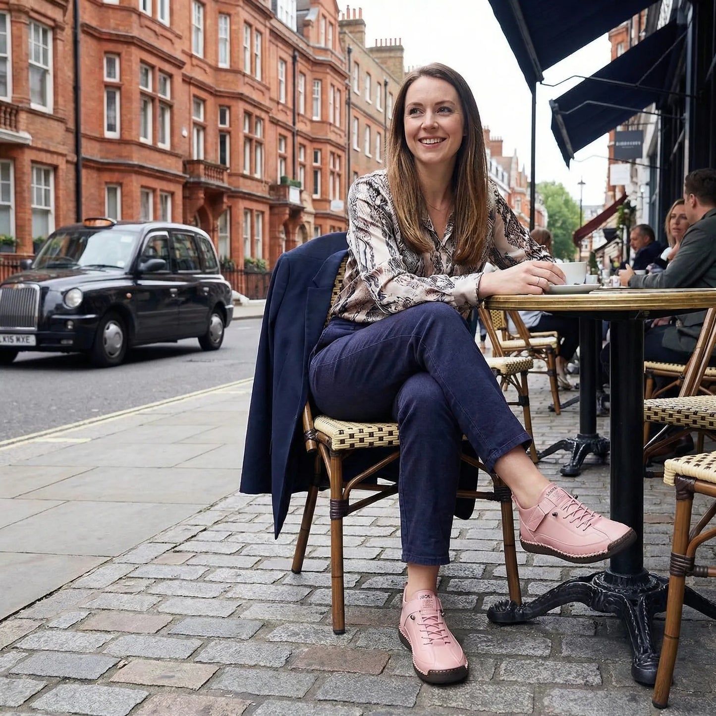 Woman wearing blush pink wide fit walking trainers at an outdoor café