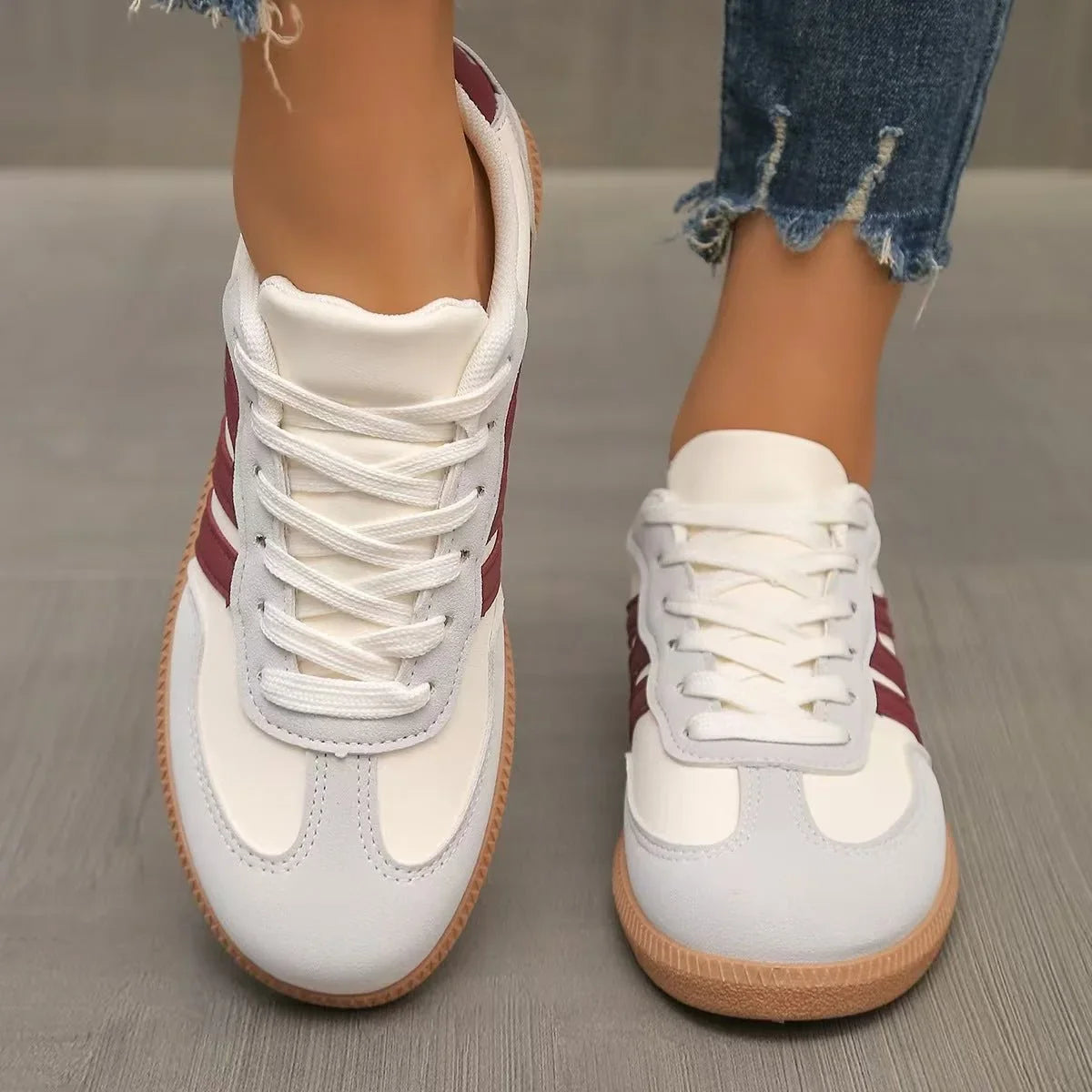 Women's white and burgundy retro trainers worn from the front