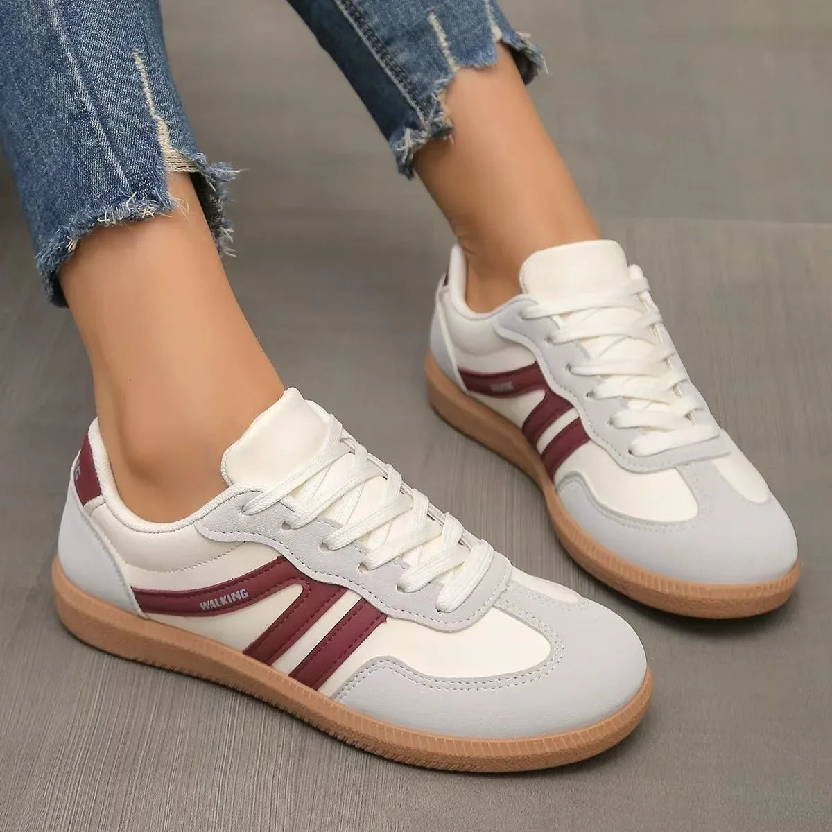 Women's white and burgundy retro trainers worn from the side