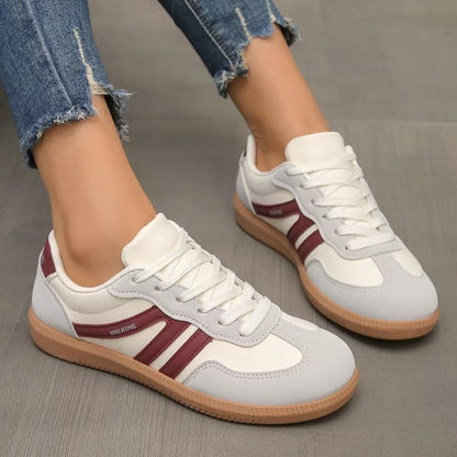 Women's white and burgundy retro trainers worn from the side