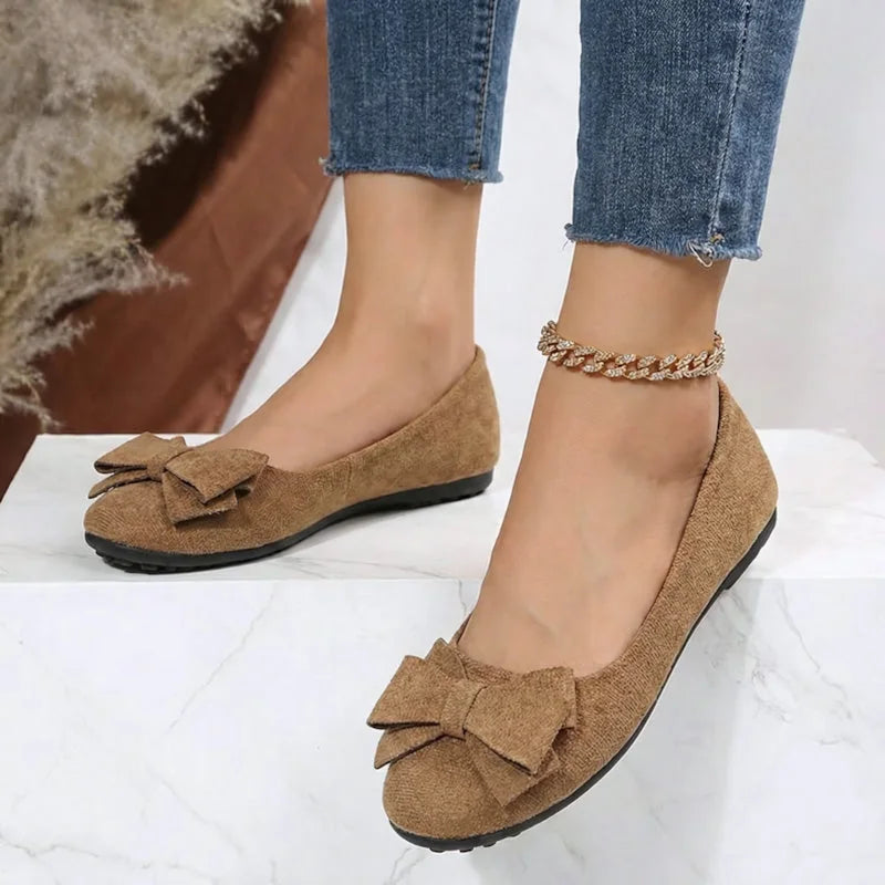 Light brown bow ballet flats worn with jeans, angled view