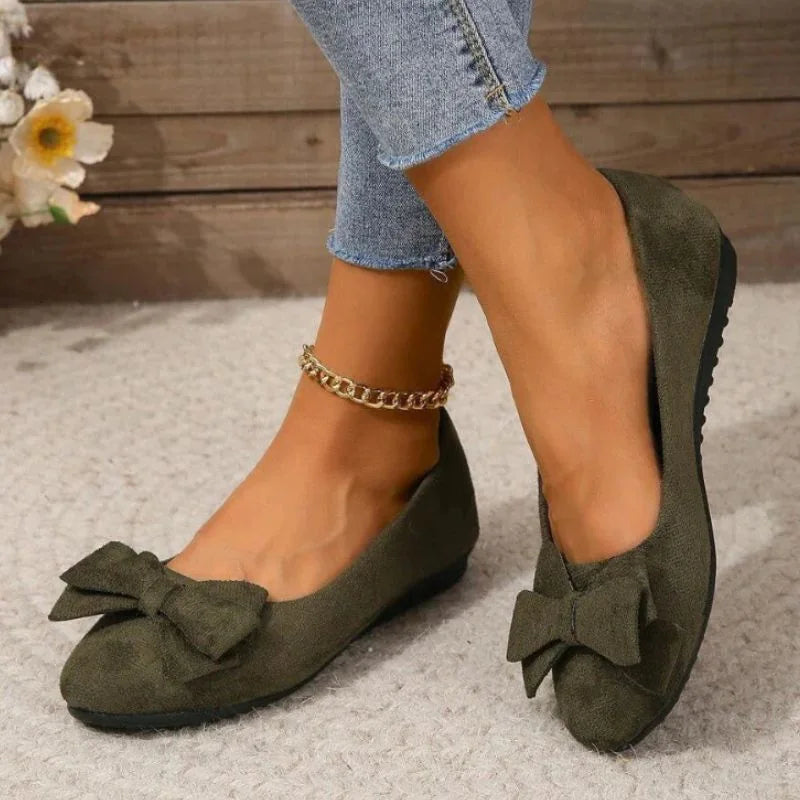 Dark green bow ballet flats worn with jeans, angled view