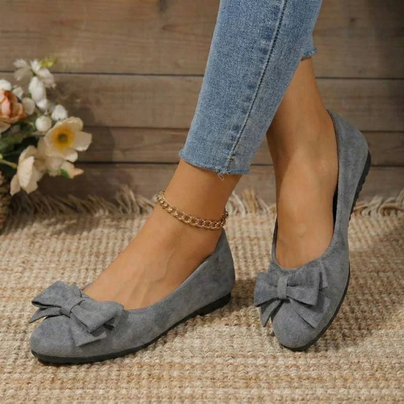 Grey bow ballet flats worn with jeans, angled view