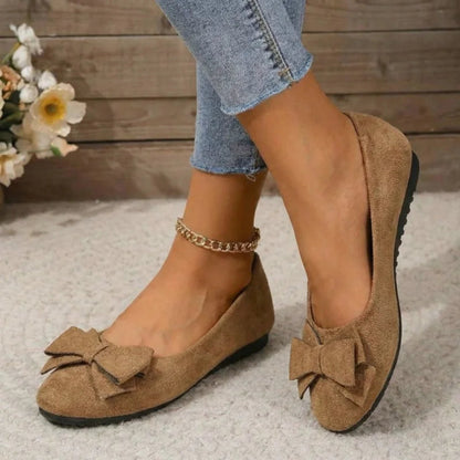 Light brown bow ballet flats worn with jeans, angled view