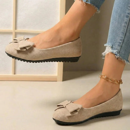 Beige bow ballet flats worn with jeans, side view