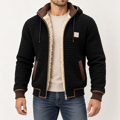 Front view of the black textured hooded jacket with brown trim worn over an oatmeal jumper.