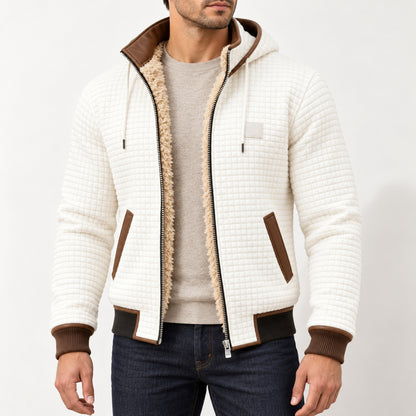 White hooded fleece-lined jacket with brown trims, worn over an oatmeal jumper with the full jacket and both hands visible.